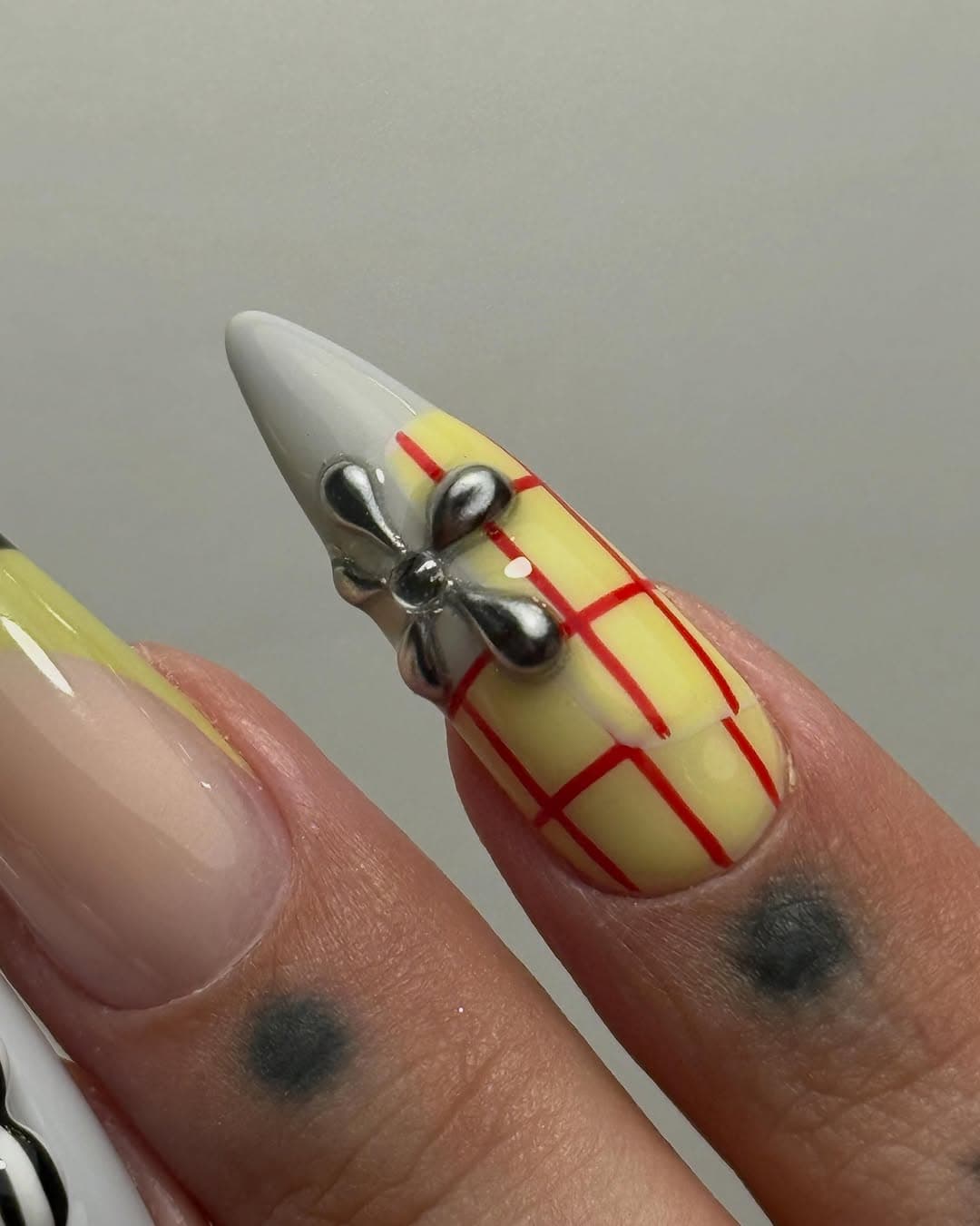 Gros plan nœud chrome 3D sur tartan jaune, nail art level 6 Lyon